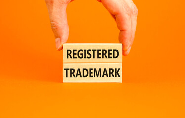 Registered trademark symbol. Concept word Registered trademark on wooden blocks. Beautiful orange table orange background. Businessman hand. Business and registered trademark concept. Copy space.