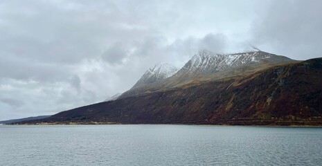 Snow capped mountains with autumn foliage along the fjords in Norway