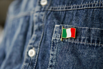 Metal badge with the flag of Italy is pinned on blue jeans jacket. Italy patriotism concept. Independence Day Holiday in Italy.