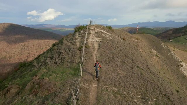 Hiker climbing to the top of Santa Barbara-Urrutxaga. Juslape&ntilde;a, Ulzama Valley in the background