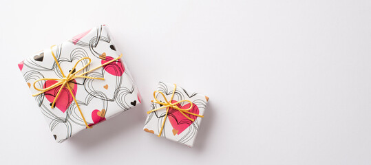 Valentine's Day concept. Top panoramic view photo of gift boxes in wrapping paper with heart pattern on isolated white background with copyspace