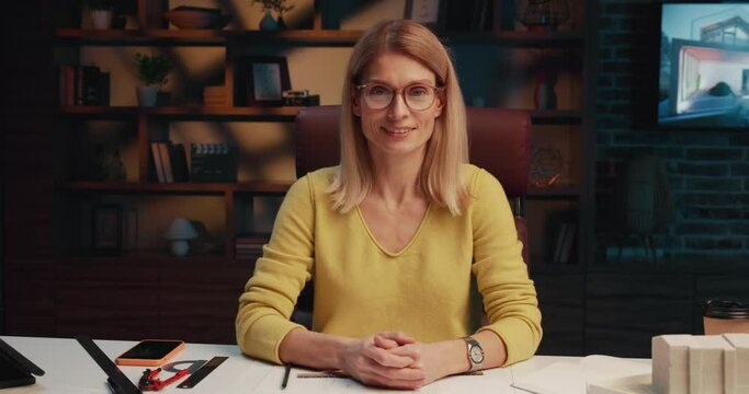 Portrait of a confident woman architect in eyeglasses sits at the office