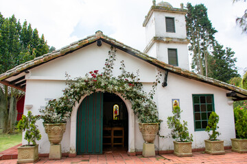 small chapel in country estate. catholic church in the countryside. white front of small church. steeple in tower. countryside