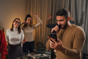 Man sings a song in the microphone on a karaoke night at home