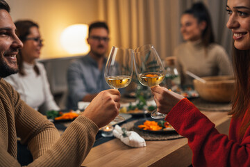 A man and a woman are having a toast at a dinner party