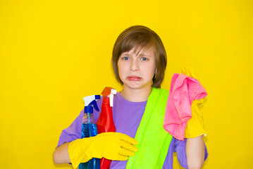 upset  boy, child, schoolboy, put on rubber gloves, holds rags for cleaning in his hands, does not want to clean up
