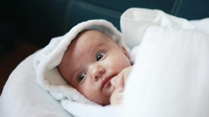 infant girl a newborn sucking thumb. happy family kid dream concept. close up cute newborn baby wrapped in bath towel at home indoors. daughter a small child sucks his thumb after lifestyle bathing