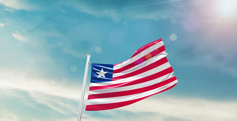 Waving Flag of Liberia in Blue Sky. The symbol of the state on wavy cotton fabric.