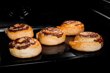 Five baked cinnamon buns on tray in electric oven. Swedish cuisine, homemade bakery, food, cooking and pastry concept