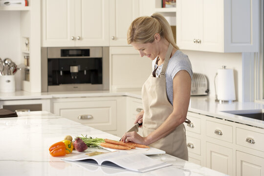 Woman Reading Cookbook in Kitchen