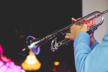 Concert view of a male trumpeter, professional trumpet player with vocalist and musical during jazz band performing