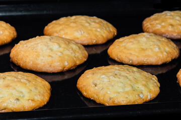 Close up view: many baked homemade crunchy oatmeal cookies on metal sheet in oven. Baking, dessert, cookery, gastronomy concept