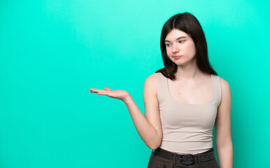 Young Russian woman isolated on green background holding copyspace with doubts