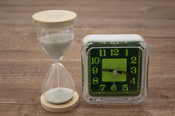 Image of a clock with hands and an hourglass. Difference between the old and the new to symbolize the passing of time.

