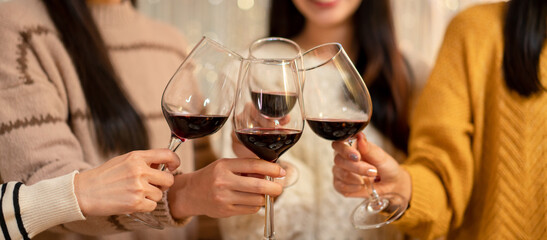 Beautiful woman clinking glass of wine to toasting with happiness while celebrating in new year party at home