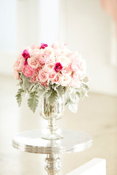 Bouquet of pink roses in silver vase on silver table, studio shot