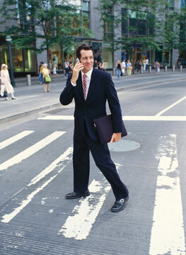 Businessman with Cellular Phone Crossing Street