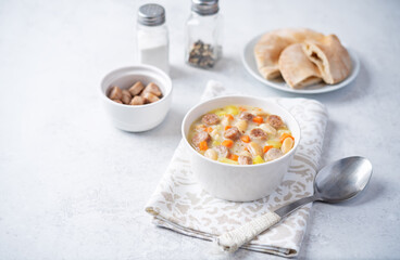 Potato carrot white bean soup with meat sausages in a bowl