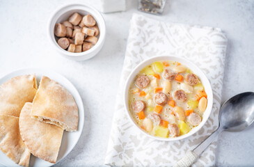 Potato carrot white bean soup with meat sausages in a bowl
