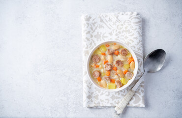 Potato carrot white bean soup with meat sausages in a bowl
