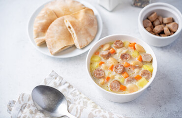 Potato carrot white bean soup with meat sausages in a bowl