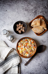 Potato carrot white bean soup with meat sausages in a bowl