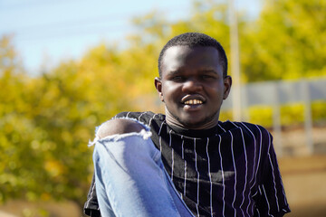 Authentic black young african boy sitting and smiling looking at camera in a park