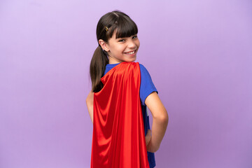 Little kid isolated on purple background in superhero costume and doingposing with arms at hip and...