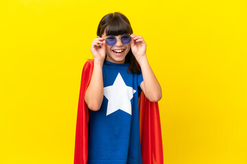 Little super hero kid isolated on purple background with glasses and surprised