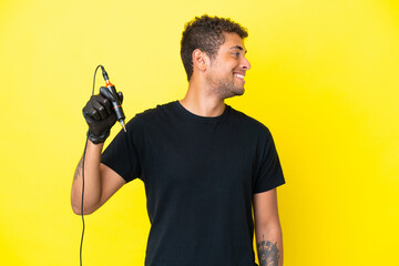 Tattoo artist Brazilian man isolated on yellow background looking side