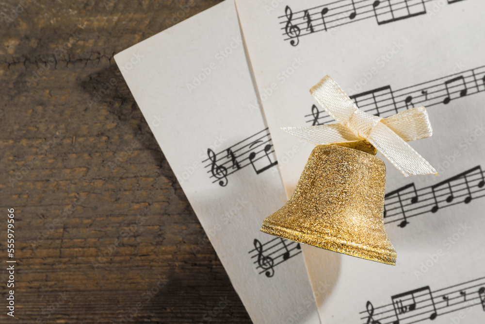 Poster golden bell and music sheets on wooden table, flat lay with space for text. christmas decor