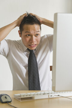 Businessman Pulling his Hair in front of Desktop Computer