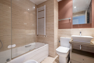 Fototapeta na wymiar small toilet with deep white porcelain sink on wooden cabinets and marble tile in white bathroom with shower screen and heated towel rail
