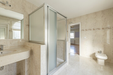 Fototapeta na wymiar Bathroom with cream marble sink, mirror with matching frame and walk-in shower with screens in the middle