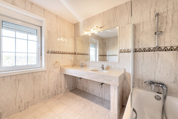 Bathroom with a white porcelain sink integrated into a cream marble countertop and a mirror integrated into the wall