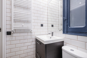 Small bathroom with a white porcelain sink on a dark wood cabinet, a shower tray with a screen, a frameless mirror and a white heated towel rail