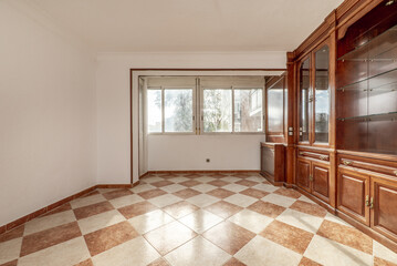 Wooden bookcase with radiator cover, drawers and doors with mirror interior inside the cabinets with glass shelves and stoneware floor in two colors and wall with two windows facing the street