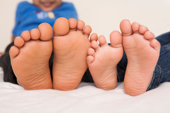Brother and sister lying in bed together, close-up of the soles of their feet, studio shot