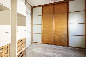 Room with built-in wardrobe from wall to wall with glass doors and Venetian sliding
