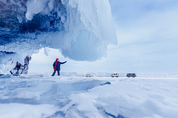 Blue ice cave grotto lake Baikal Russia and car for tourist travel. Beautiful winter landscape with man traveler © Parilov