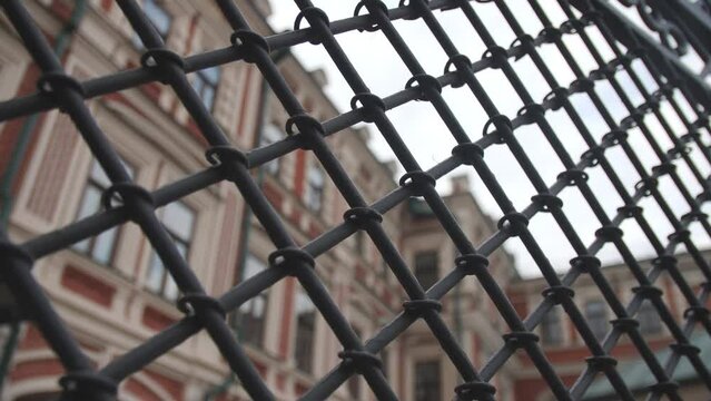 Metal grid fence against elegant old building on city street closeup. Architectural heritage protection program