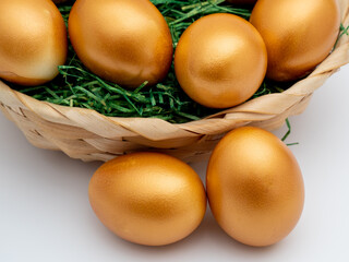 Golden eggs in a wicker basket on a white background. Golden chicken eggs.