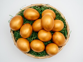 Golden eggs in a wicker basket on a white background. Golden chicken eggs.