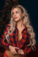 A bright blonde with long hair in a New Year's look near the Christmas tree - 555986361