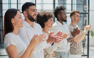 Group of businesspeople sitting in a line and applauding.