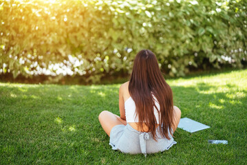 Young fit attractive woman lying on green lawn park.