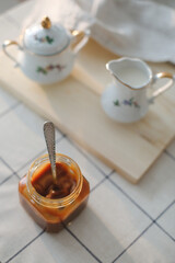 Homemade salted caramel sauce in jar on rustic wooden table.