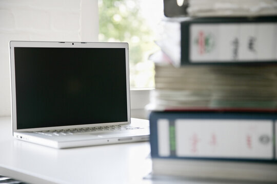Stacked Binders and Laptop Computer on Office Desk