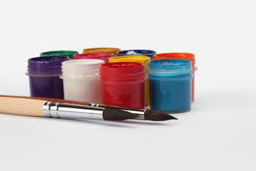 Acrylic paints in boxes, brushes on white background.