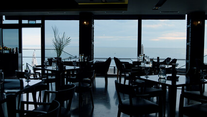 Dark interior in modern panoramic bar. Scenic ocean view in luxury lounge cafe